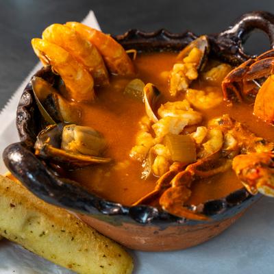 Seafood stew with shrimp, crab, and mussels served with a breadstick.