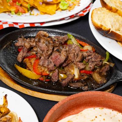 Steak Quesadillas on a hot plate with multiple sides around it..