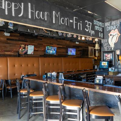 Interior featuring a long bar counter with stools, leather seating, and TVs.