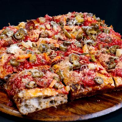Square focaccia pizza slices topped with pepperoni, grated cheese, and peppers.