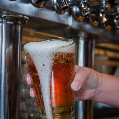 A glass of beer being poured from a tap.