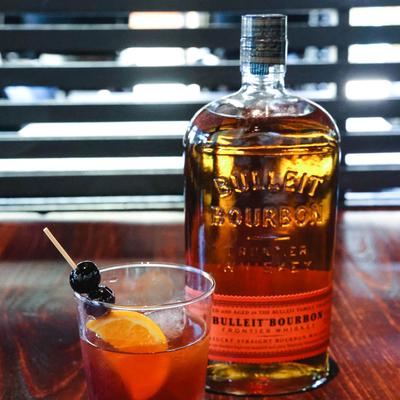 A bottle of bourbon and a cocktail in a glass.