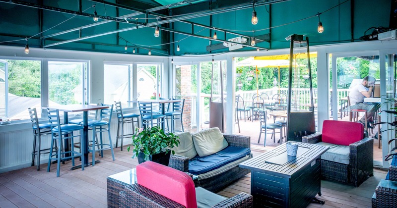 Indoor lounge area, wicker furniture, tables under a turquoise ceiling, opening to a patio view