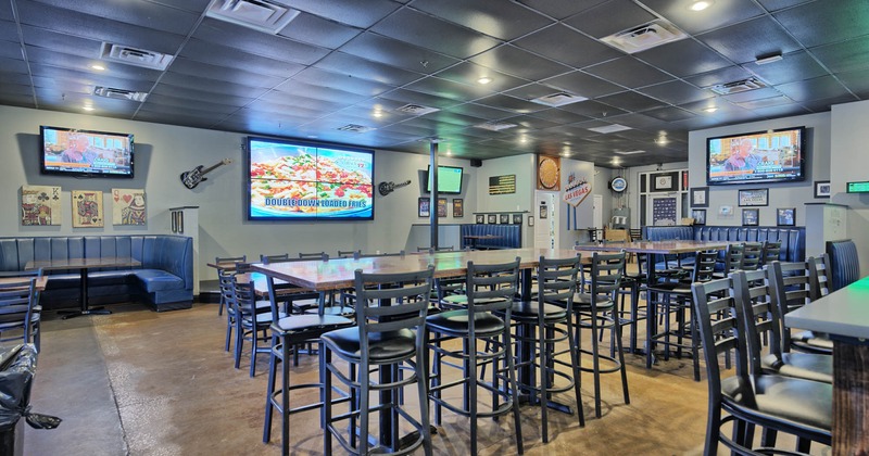 Interior, tall tables and chairs, round booths , TVs and decorations on walls