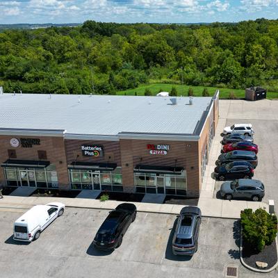 Commercial retail strip center building featuring storefront glass windows and parked vehicles.