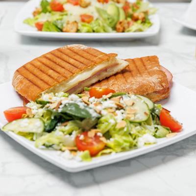Grilled ham and cheese panini with fresh garden salad topped with cheese and almonds.