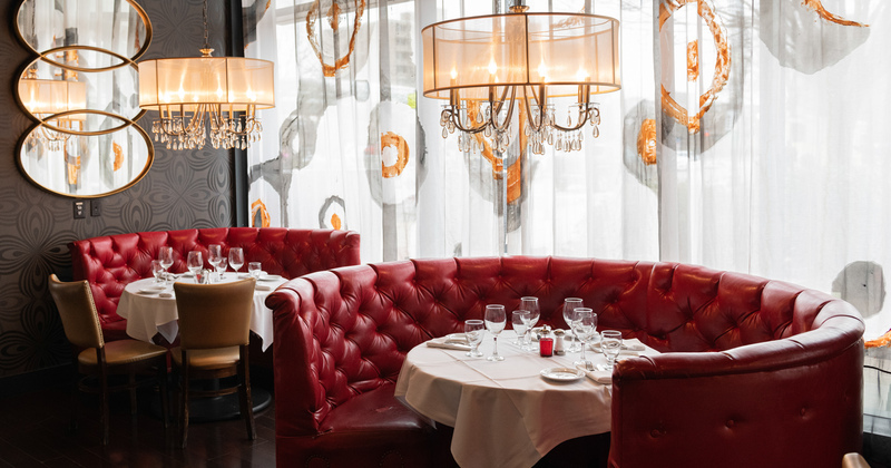 Interior, private round leather booth seating with set tables by a curtained window