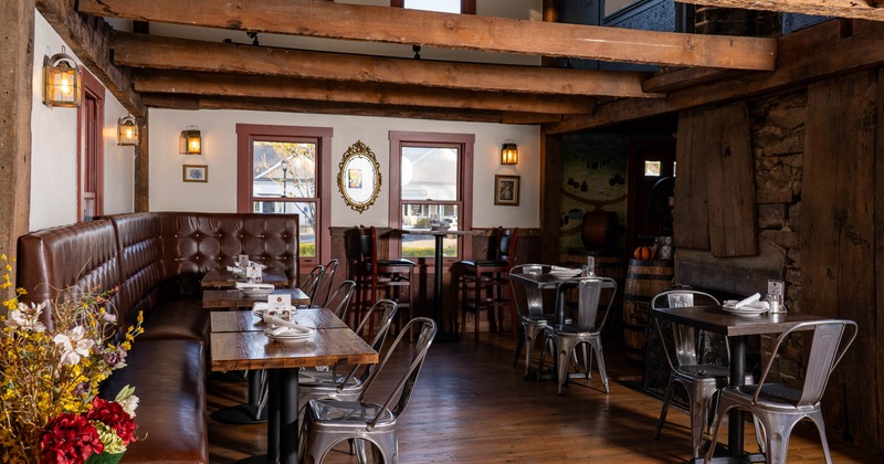 Rustic restaurant interior with wooden beams, leather seating, and metallic chairs