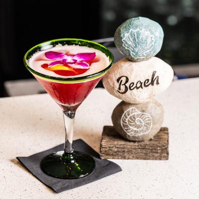 Cocktail in a martini glass next a decorative stack of three stones.