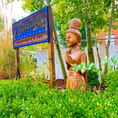 Exterior, restaurant wooden logotype sign with a wood sculpture, and a lot of greenery