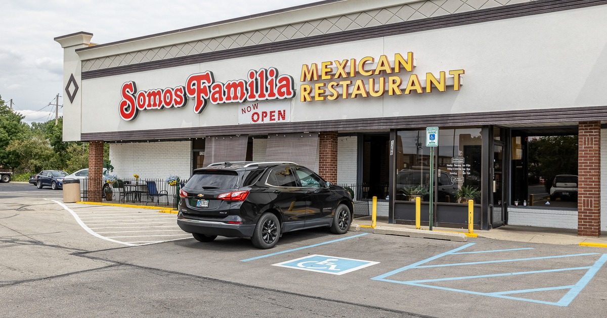 Exterior, angle view to restaurant entrance and parking lot, sign above