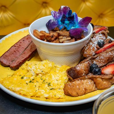 French toast served with scrambled eggs, pork sausage, and fried potatoes.