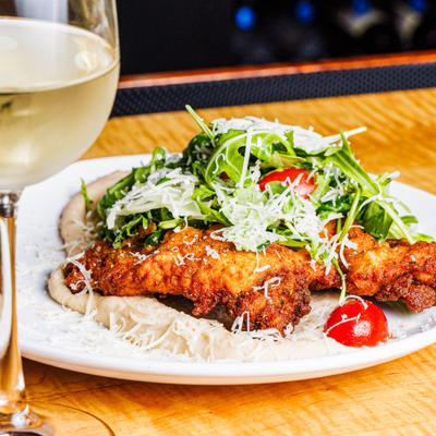 Chicken Milanese with white bean puree, arugula salad, and a glass of white wine.