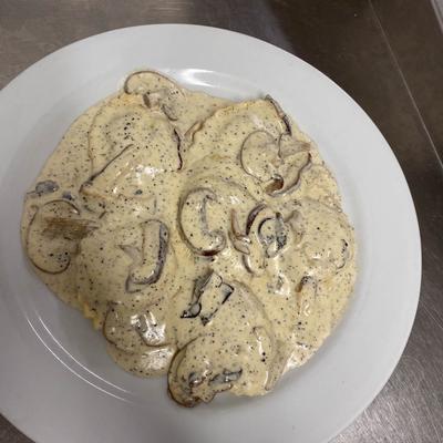 A plate of pasta covered in a creamy sauce with mushrooms and black peppers.