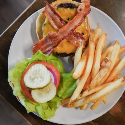 Eagle Burger topped with bacon alongside fries.