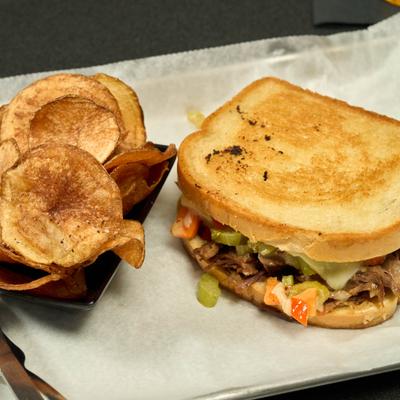 Big beef pot roast sandwich with chips.