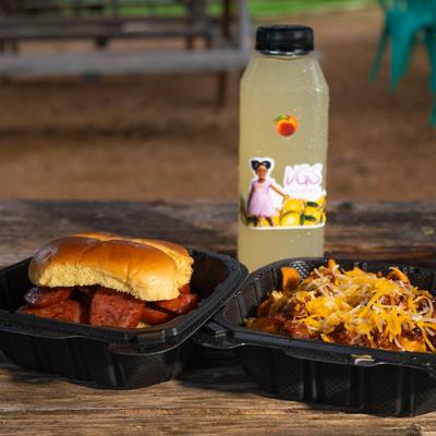 Barbecue sausage sandwich with chili cheese fries and a bottled lemonade on a table.