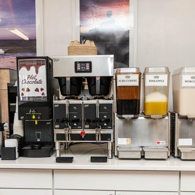 Beverage station with dispensers for hot chocolate, pineapple juice, and iced coffee.