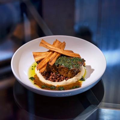 Braised lamb shoulder accompanied by mashed potato, topped with fried plantains.