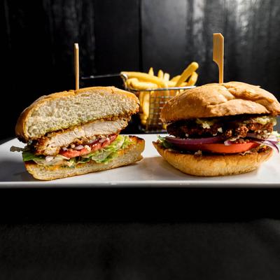 Fried chicken sandwich, with lettuce, tomato, onion, and fries.