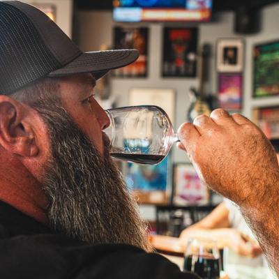 A person takes a sip of red wine.