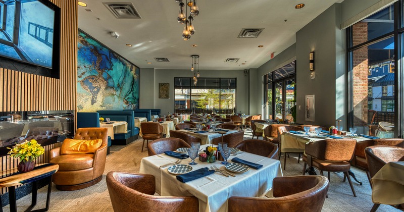 A modern interior - set tables, leather chairs, a blue mural, pendant lights and large windows