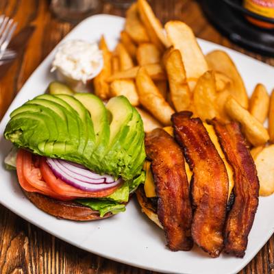 Bacon cheeseburger topped with avocado slices, served with fries.