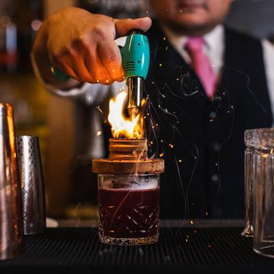 A bartender makes flame above the Negroni cocktail.