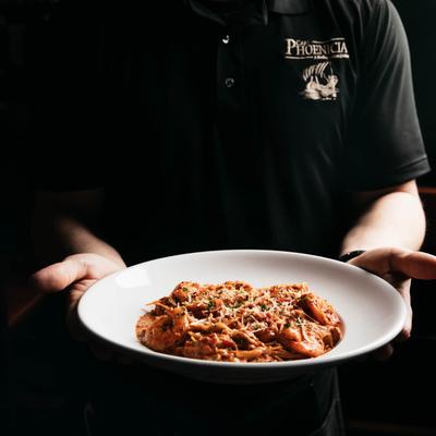 Staff member holding a plate with seafood pasta