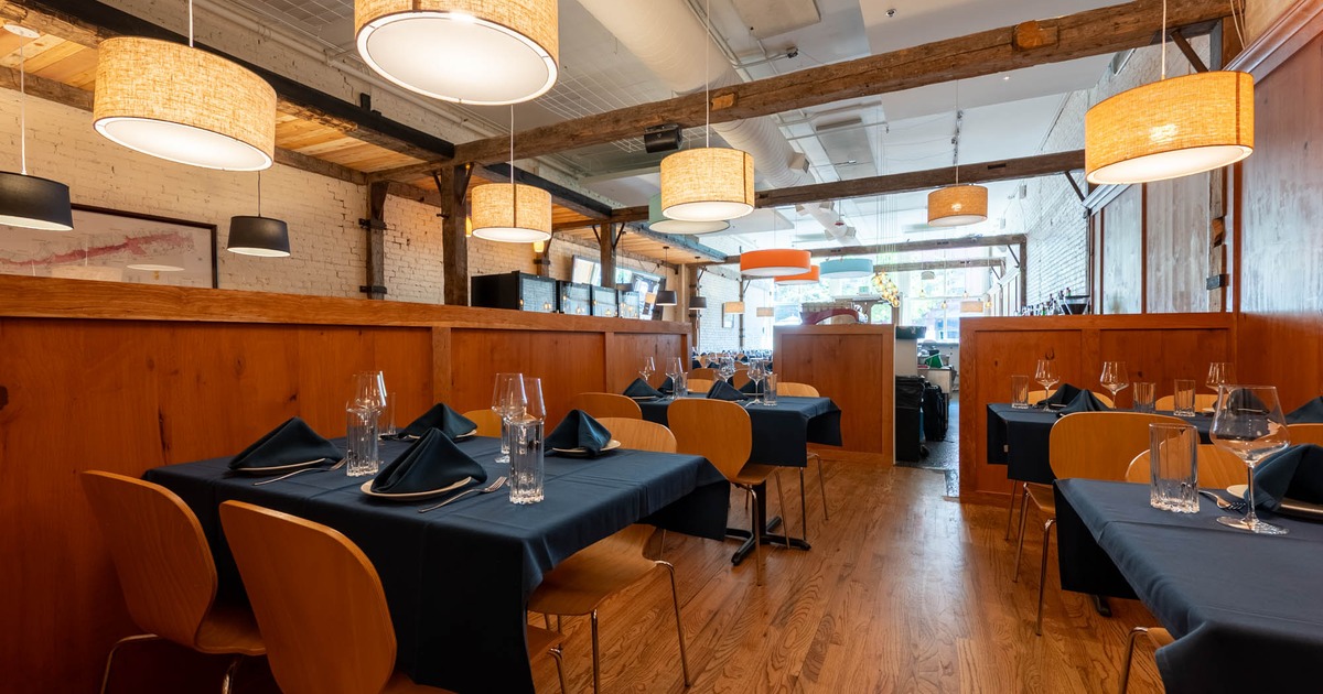 Interior with wooden floors, modern lamps, and dark tablecloths on neatly set tables