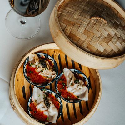 Dumplings in sauce served in bamboo steamer.