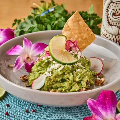 A bowl of guacamole garnished with a flower.