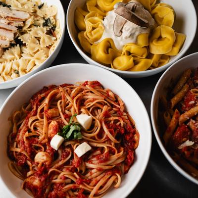 Four bowls of pasta featuring tortellini, penne, bowties with chicken, and linguine in tomato sauce.