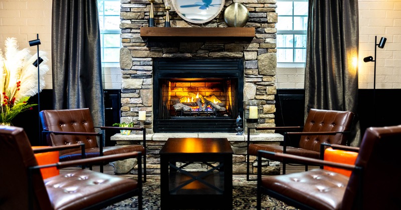 Interior, lounge area, armchairs with coffee tables, built in fire place, stone wall