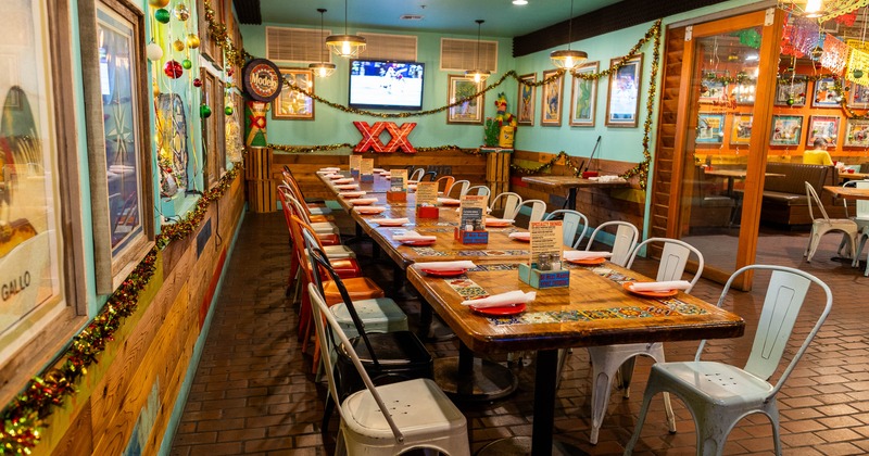 Festive interior with a long dining table surrounded by colorful chairs and bright decorations