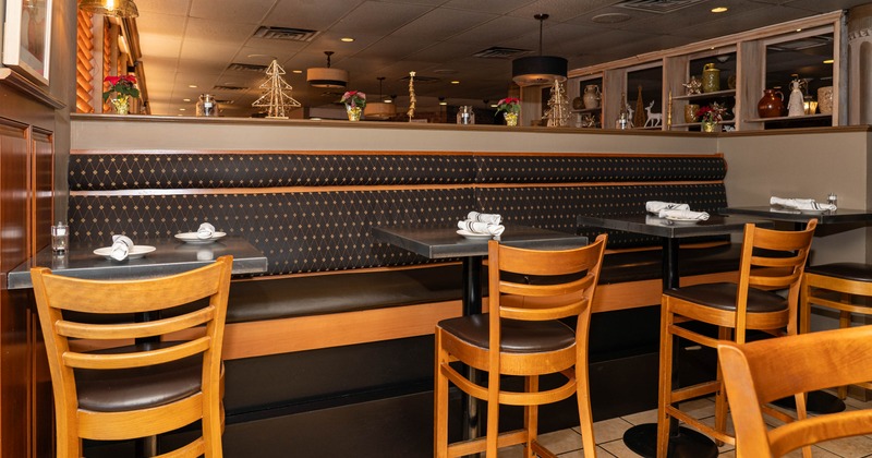 A restaurant interior with booths, small tables, wooden chairs, and festive decorations
