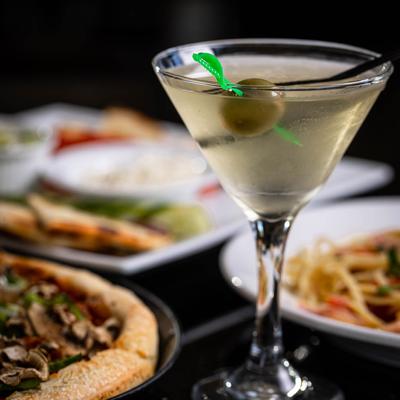 Glass of Martini surrounded by multiple food plates, closeup