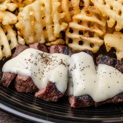 Steak with melted cheese and waffle fries