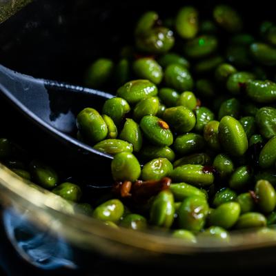 Edamame in a dark bowl, close up.
