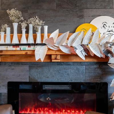 Interior, decorative items on a wall above an electric fireplace.