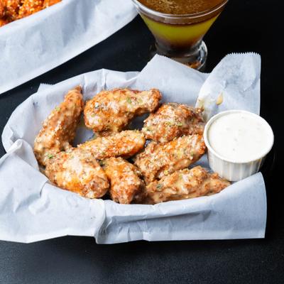 Garlic Parmesan wings paired with creamy sauce and a cocktail.