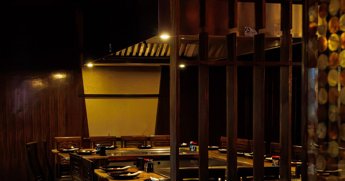 Interior of cozy dining area with wooden teppanyaki-style table, equipped with a built-in grill