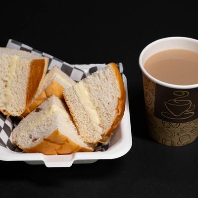 A soft bun with a layer of cream, served with a cup of tea.