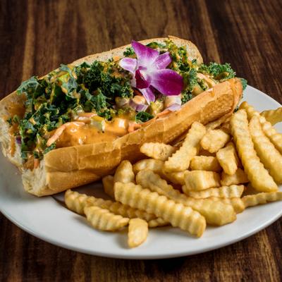 Catfish Po'Boy topped with kale and sauce, served with crinkle fries.