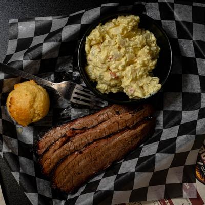 Brisket served with potato salad and a corn muffin, top view.