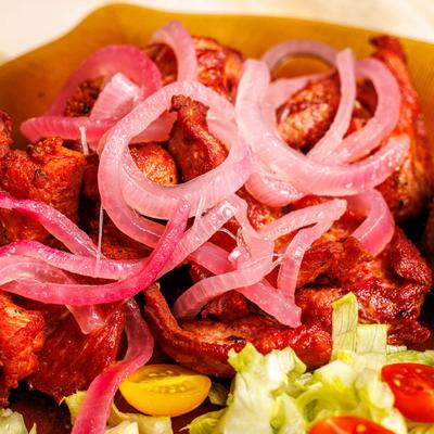 Fried pork belly chunks with pickled onions, lettuce, and cherry tomatoes.