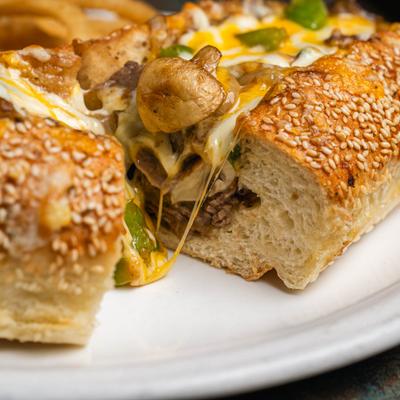 Philly cheesesteak sandwich with mushrooms on sesame bread.