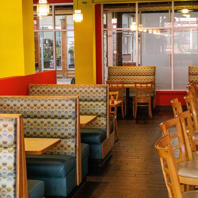 Interior featuring booth seating with patterned vinyl upholstery and yellow walls.