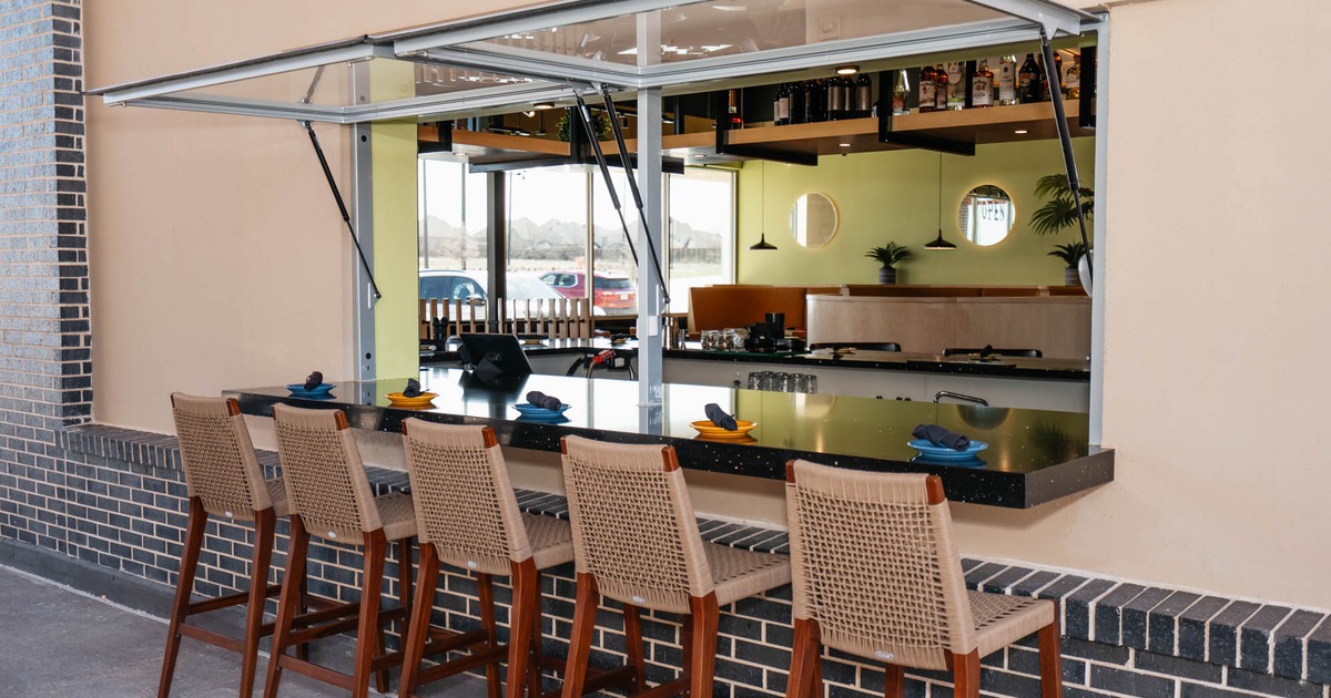 Exterior, marble top bar looking outside in, stools, ready for guests, low brick wall
