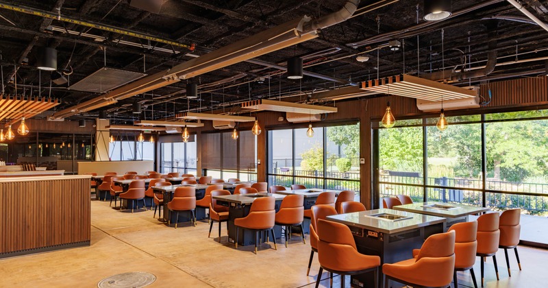 Interior seating area with orange seating and black tables with glass tops